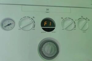 Close-up of an Ideal boiler control panel showing an error code F1, indicating a pressure issue and troubleshooting in progress.