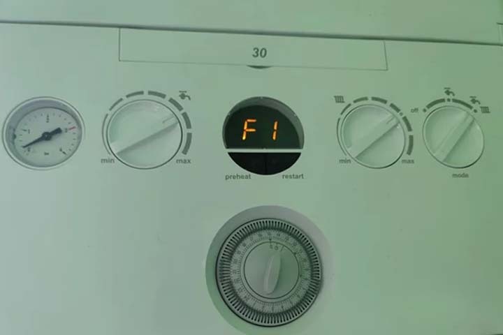 Close-up of an Ideal boiler control panel showing an error code F1, indicating a pressure issue and troubleshooting in progress.
