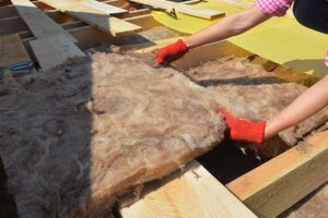 UK homeowner installing loft insulation to cut heating costs and improve energy efficiency