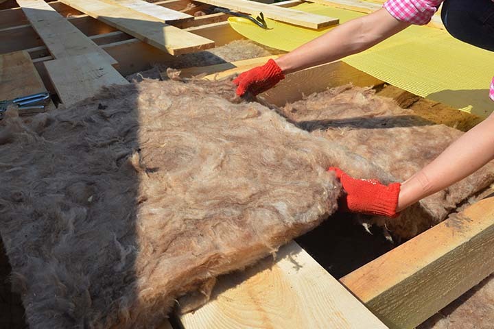 UK homeowner installing loft insulation to cut heating costs and improve energy efficiency